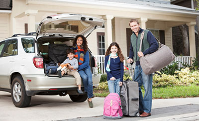 a family packing in their driveway getting ready to go on a trip